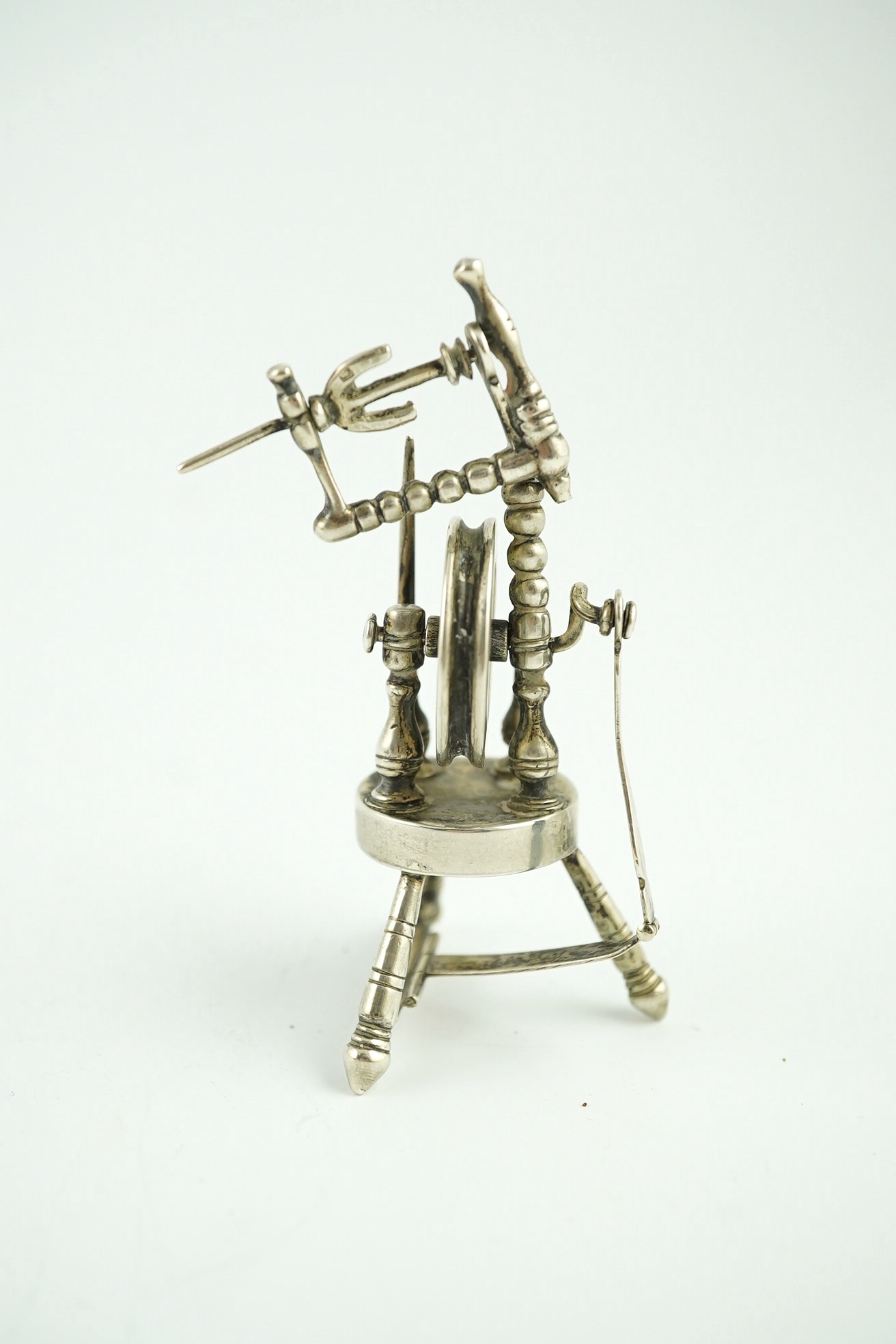 An Edwardian silver miniature articulated model spinning wheel, by Deakin and Francis Ltd, Birmingham 1905, 8.5cm and a cased set of coffee spoons, Sheffield 1936, with ‘bean’ terminals. Condition - fair